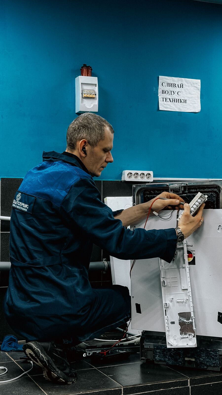 Technician testing a dishwasher control panel with a multimeter probe