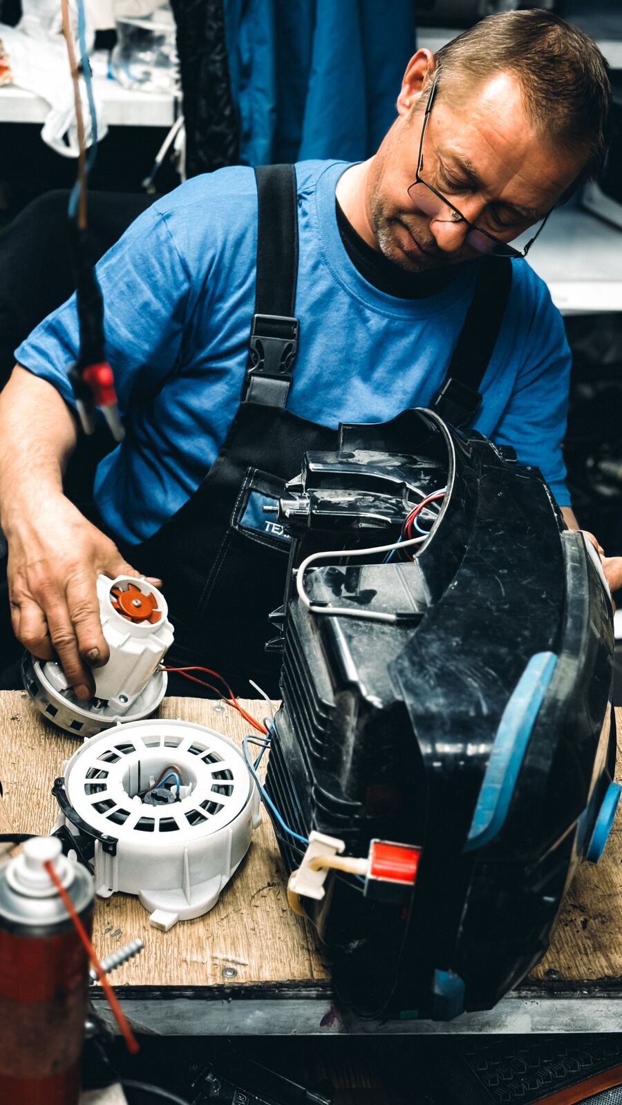 Technician fitting a new motor into a vacuum cleaner on the workbench